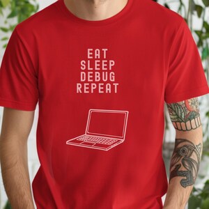 Pode incluir: Camiseta vermelha com a frase branca "EAT SLEEP DEBUG REPEAT" e um contorno branco de um laptop. A camiseta de manga curta é feita de um tecido macio.