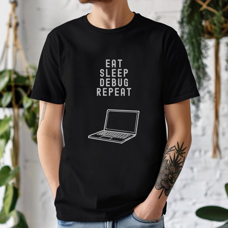 May include: Black t-shirt with the text "EAT SLEEP DEBUG REPEAT" in white, along with a white line drawing of a laptop. The shirt is a crew neck and has short sleeves.