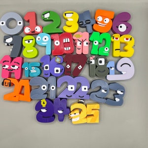 Puede incluir: Un conjunto de 25 bloques de números coloridos y de aspecto de dibujos animados con diferentes expresiones faciales. Cada bloque es de un color diferente y tiene un número del 0 al 25.