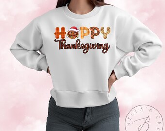 May include: White sweatshirt with a festive Thanksgiving design. The text "Happy Thanksgiving" is printed in brown with a cartoon turkey wearing a Santa hat in the middle of the word "Happy".