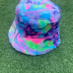 May include: A fuzzy bucket hat with a swirl pattern in shades of pink, blue, green, and purple.