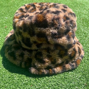 Può includere: Un cappello a secchiello marrone e nero con stampa leopardata in finta pelliccia.