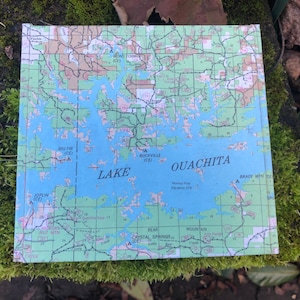 May include: A map of Lake Ouachita in Arkansas, showing the lake's shoreline, surrounding roads, and nearby towns. The map is printed on a light blue background with green and brown lines.