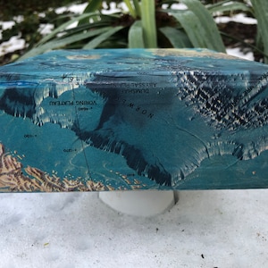 May include: A blue box with a map of the ocean floor. The map shows the Vøring Plateau, the Norwegian Sea, and the Abyssal Plain. The box is sitting on a white surface.