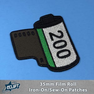 May include: A black and white embroidered iron-on or sew-on patch of a 35mm film roll with the text "200" on it. The film roll is green and white.
