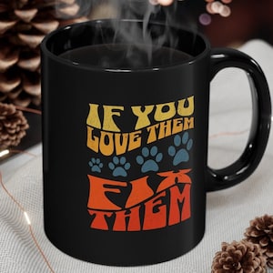 May include: Black coffee mug with a retro-style graphic that says "If you love them fix them" with paw prints.