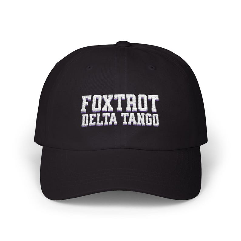 Może przedstawiać: Czarna czapka bejsbol&oacute;wka z białym haftem z napisem "FOXTROT DELTA TANGO".