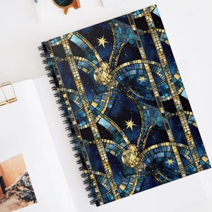 May include: A spiral bound notebook with a blue and gold mosaic design featuring stars and celestial bodies. The design is reminiscent of stained glass.
