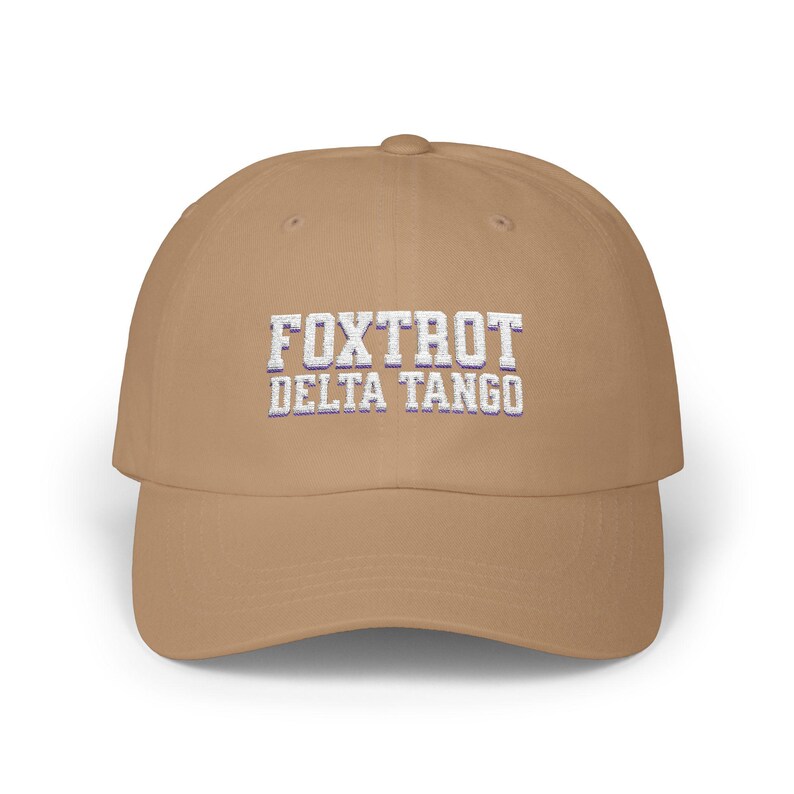 Może przedstawiać: Beżowa czapka z daszkiem z haftowanym białym tekstem "FOXTROT DELTA TANGO".