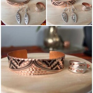May include: A set of copper jewelry featuring a bracelet, a ring, and a pair of earrings. The bracelet and ring have a hammered texture and a geometric pattern. The earrings are silver with a leaf design.