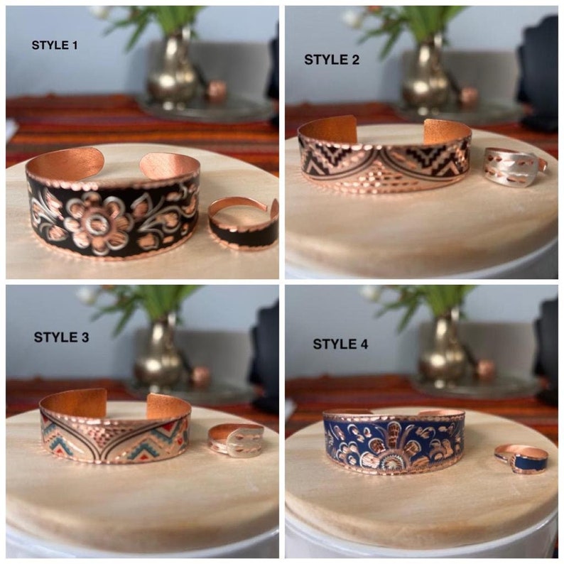 May include: Four different styles of copper bracelets with matching rings. Each bracelet has a unique design with black, blue, and white enamel. The bracelets are displayed on a wooden surface.