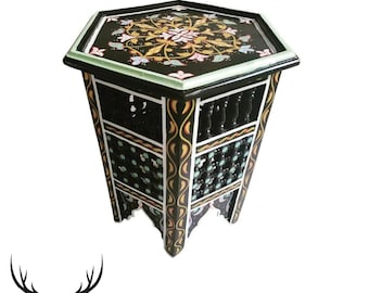 May include: A black hexagonal side table with intricate hand-painted floral designs in shades of pink, yellow, and green. The table has a carved wooden base with a geometric pattern.