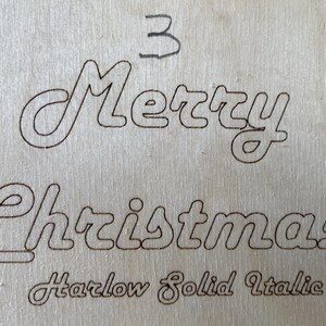 May include: A wood sign with the words "Merry Christmas" in a cursive font. The font is labeled "Harlow Solid Italic".