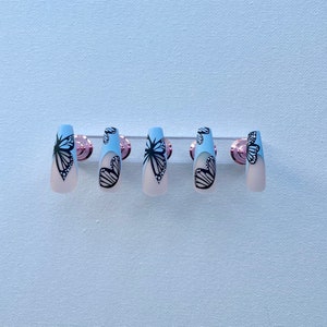 青いフレンチチップの蝶がネイルに押し付けられる