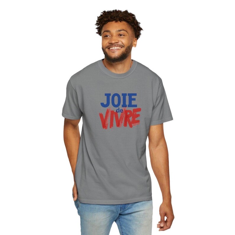 Puede incluir: Una camiseta gris de manga corta con el texto JOIE en letras azules sobre la palabra de en letras azules peque&ntilde;as y VIVRE en letras rojas grandes con estilo de pincelada, centradas en el pecho de la prenda.