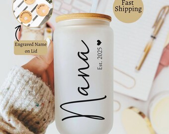 May include: A frosted glass tumbler with a bamboo lid and straw. The tumbler is inscribed with the word "Nana" in black script, along with "Est. 2025" and a heart symbol. The lid has engraved wooden coasters with names.