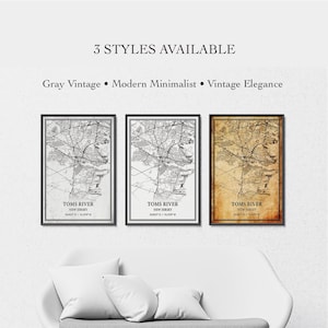 Può includere: Tre stampe da parete incorniciate con mappe di Toms River, New Jersey, e coordinate. Il testo recita 3 STYLES AVAILABLE, Gray Vintage, Modern Minimalist e Vintage Elegance. Le stampe sono esposte in cornici nere sopra un divano bianco.