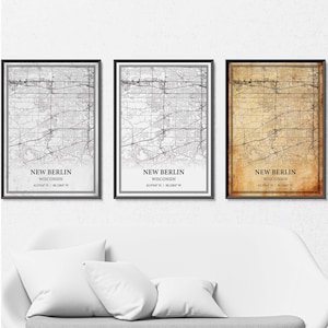 Op de afbeelding: Drie ingelijste kaarten van New Berlin, Wisconsin, in zwarte lijsten. Twee kaarten zijn zwart-wit en één is sepia getint. Elke kaart bevat de stadsnaam en coördinaten.
