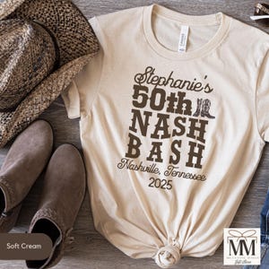 May include: A beige t-shirt with a brown graphic design that says "Stephanie's 50th Nash Bash Nashville, Tennessee 2025".