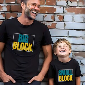 May include: Two people wearing black t-shirts with a yellow and teal graphic. The larger t-shirt says "BIG BLOCK" and the smaller t-shirt says "SMALL BLOCK".