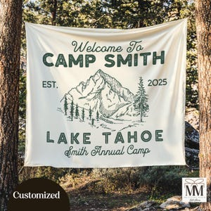 May include: A white canvas banner with green text and a mountain scene. The text reads "Welcome to Camp Smith Est. 2025 Lake Tahoe Smith Annual Camp".