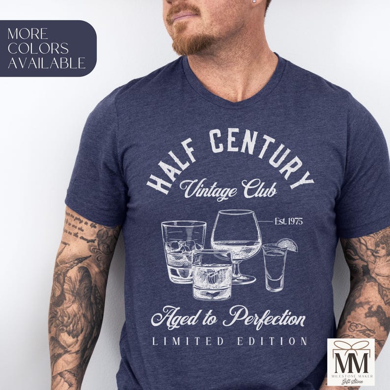 May include: A navy blue t-shirt featuring a white graphic with the text "HALF CENTURY Vintage Club" and "Aged to Perfection, Limited Edition." The design includes illustrations of different glasses. The text "Est. 1975" is also visible.