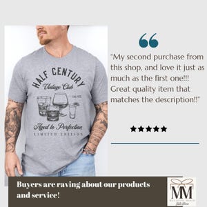 May include: A grey t-shirt with a graphic design. The design includes the text "HALF CENTURY Vintage Club" and illustrations of cocktail glasses. The shirt also features the text "Aged to Perfection" and "LIMITED EDITION".