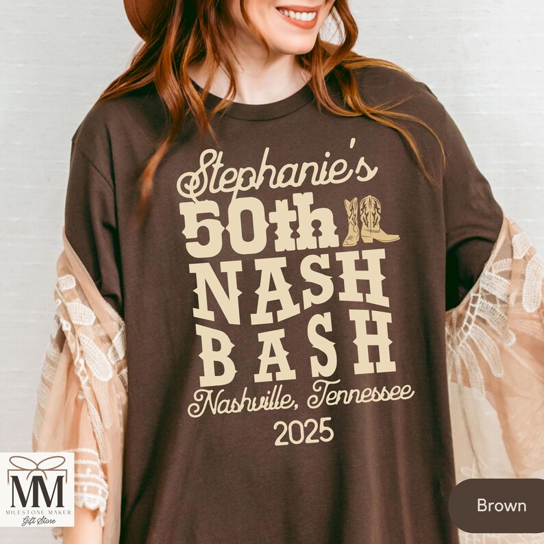 May include: Brown t-shirt with the text "Stephanie's 50th NASH BASH Nashville, Tennessee 2025" in beige lettering. The text is decorated with a pair of brown cowboy boots.