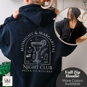 Puede incluir: Sudadera con capucha azul marino con cremallera completa y un gráfico blanco en la espalda que dice "Midnight & Margaritas Night Club". El diseño incluye una copa de margarita, una luna creciente y el texto "Drink Up Witches".