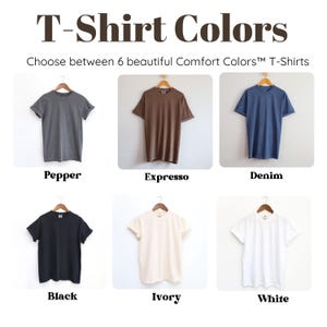 May include: Image showcasing six Comfort Colors&trade; T-shirts in various hues. The colors include Pepper, Expresso, Denim, Black, Ivory, and White. Each shirt is displayed on a wooden hanger against a neutral background. The text "T-Shirt Colors" is at the top.