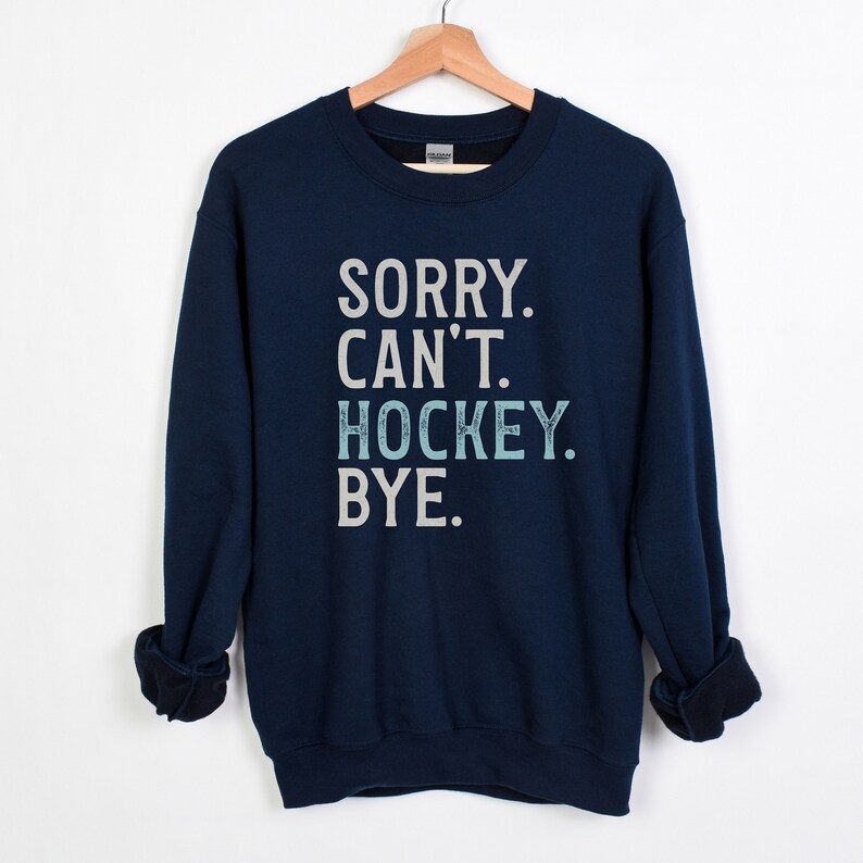 May include: Navy blue sweatshirt with the text "SORRY. CAN'T. HOCKEY. BYE." in white and light blue lettering.