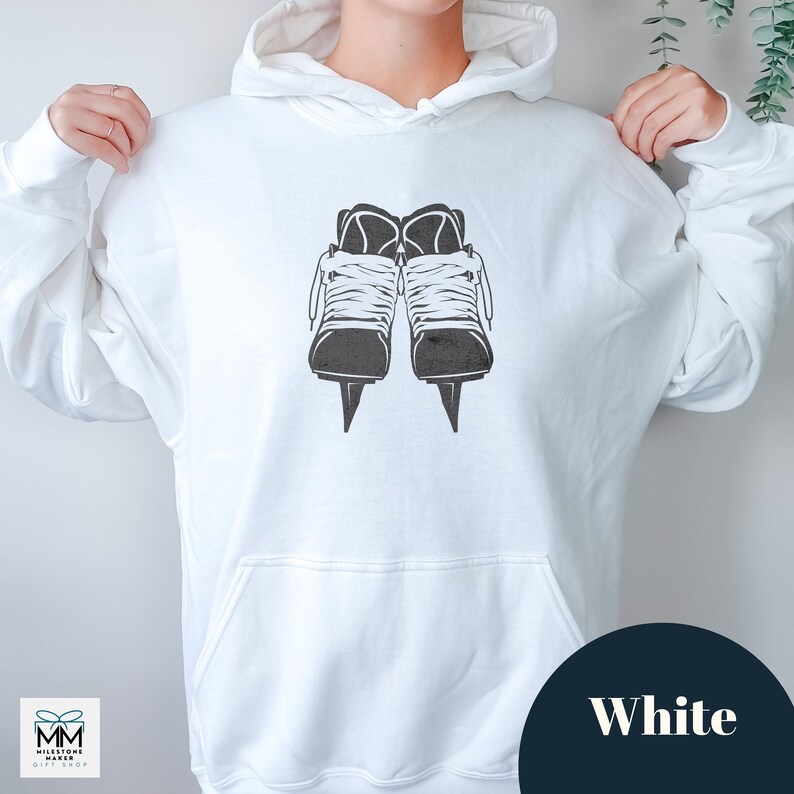 Op de afbeelding: Witte hoodie met een zwart-witte afbeelding van schaatsen. De afbeelding is gecentreerd op de voorkant van de hoodie.
