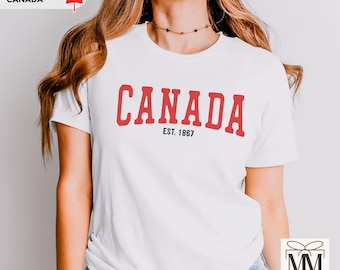May include: White t-shirt with red text that says "CANADA EST. 1867".