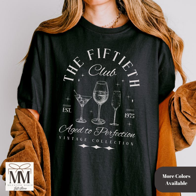 May include: Black t-shirt with a white graphic that reads "The Fiftieth Club" with wine glasses and the text "Aged to Perfection". The shirt also has the text "EST. 1975" and "Vintage Collection".