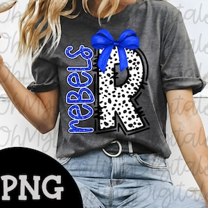 May include: Gray t-shirt featuring a large letter "R" with a black and white dalmatian print, a blue bow, and the word "Rebels" in blue. The design is centered on the shirt.