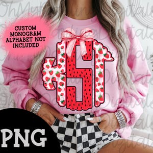 Op de afbeelding: Een roze sweatshirt met een watermeloen- en aardbeienmonogramdesign. Het monogram is een grote letter "S" met een roze strik erop. De tekst "CUSTOM MONOGRAM ALPHABET NOT INCLUDED" staat op het sweatshirt gedrukt.
