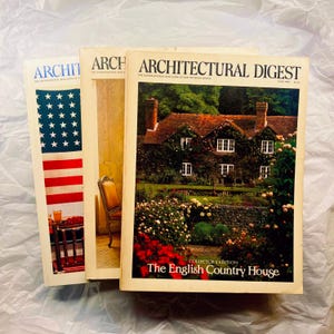 May include: Three vintage Architectural Digest magazines. The covers feature an American flag, a chair, and a house with a garden. The magazine on the right is the "Collector's Edition" with the title "The English Country House."