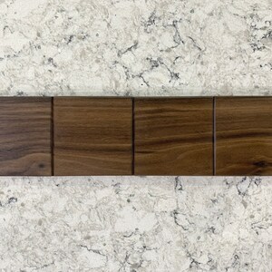 May include: Four wood samples in a row, each a different shade of brown. The wood has a natural grain pattern.