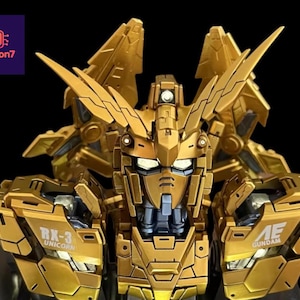 Può includere: Modello RX-3 Unicorn Gundam dorato, con intricati dettagli meccanici e angoli acuti. Il modello presenta il testo "RX-3 Unicorn" e "AE GUNDAM" sull'armatura. Lo sfondo è nero.
