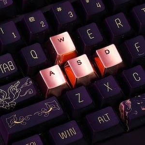 May include: A close-up of a keyboard with rose gold keycaps. The keys are labeled with the letters 'Q', 'W', 'E', 'R', 'T', 'Y', 'U', 'I', 'O', 'P', 'A', 'S', 'D', 'F', 'G', 'H', 'J', 'K', 'L', 'Z', 'X', 'C', 'V', 'B', 'N', 'M'.
