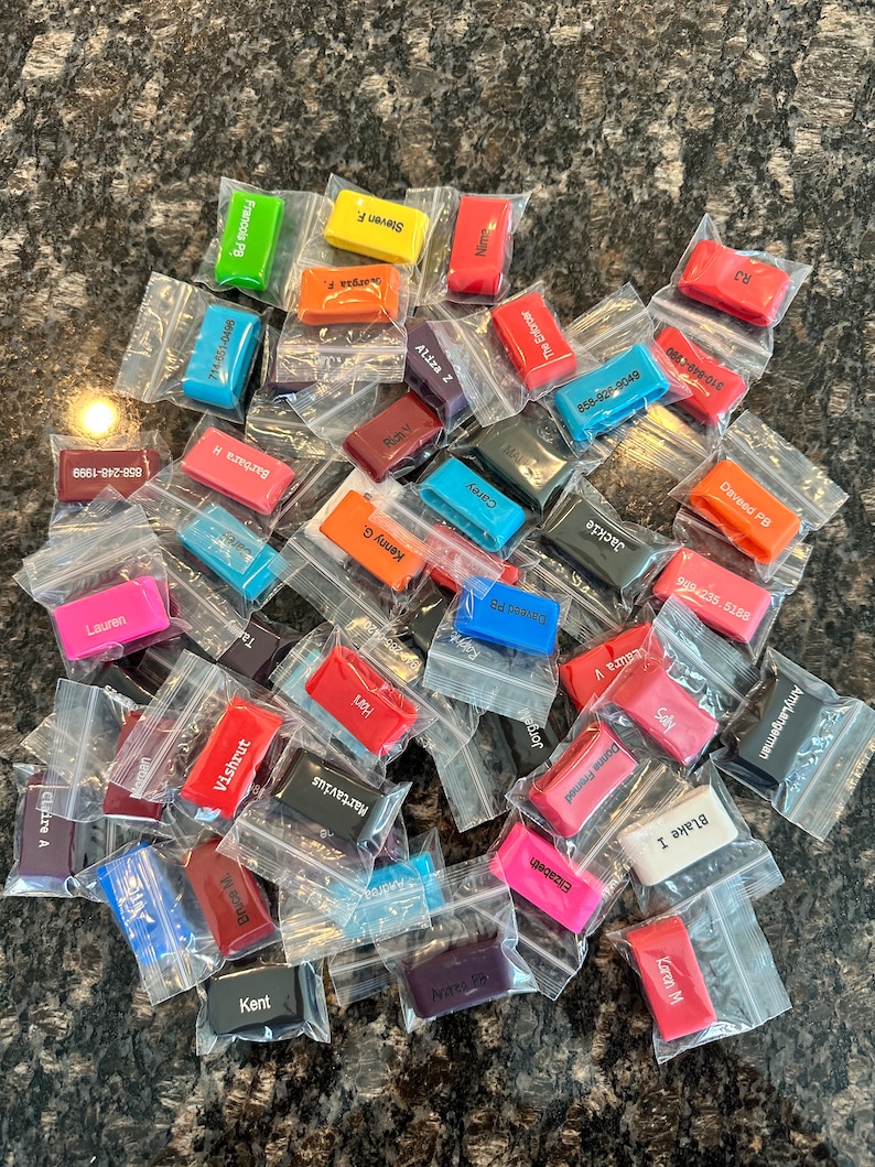 Puede incluir: Una colecci&oacute;n de llaveros de silicona de colores con varios nombres impresos en ellos. Los llaveros est&aacute;n empaquetados en bolsas de pl&aacute;stico transparentes individuales.