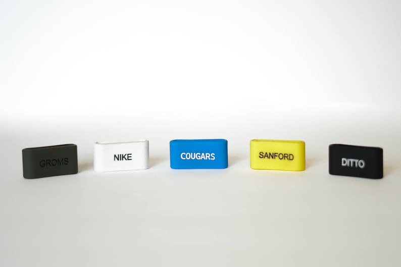 Puede incluir: Cinco llaveros rectangulares de diferentes colores con texto blanco. Los llaveros est&aacute;n etiquetados como "Groms", "Nike", "Cougar", "Sanford" y "Ditto".