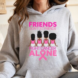 May include: Grey hoodie with a pink graphic design featuring four women with pink shirts and white jeans. The text reads "Friends don't let friends fight cancer alone" with a pink ribbon.