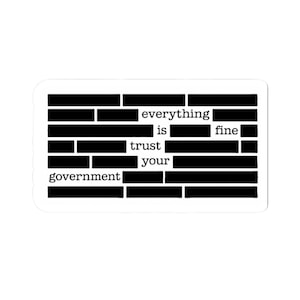 May include: A white sticker with black text that reads "everything is fine trust your government." The words are partially obscured by black bars, creating a censored effect. The sticker has a rectangular shape with rounded corners.