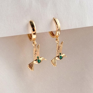 Pendentifs Huggie Hoops avec breloque colibri dans des tons dorés et argentés.