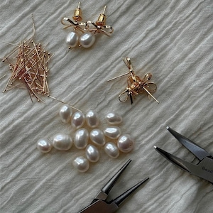 Flatlay of earrings in progress with tools and loose pearls. Behind-the-scenes craftsmanship moment that highlights handmade jewelry authenticity.