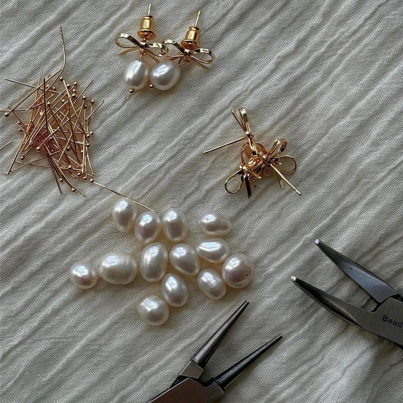 Flatlay of earrings in progress with tools and loose pearls. Behind-the-scenes craftsmanship moment that highlights handmade jewelry authenticity.