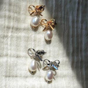 AFlatlay of gold and silver versions of the earrings on striped cloth. A versatile pair for bridal earrings or bridesmaid jewelry styling.