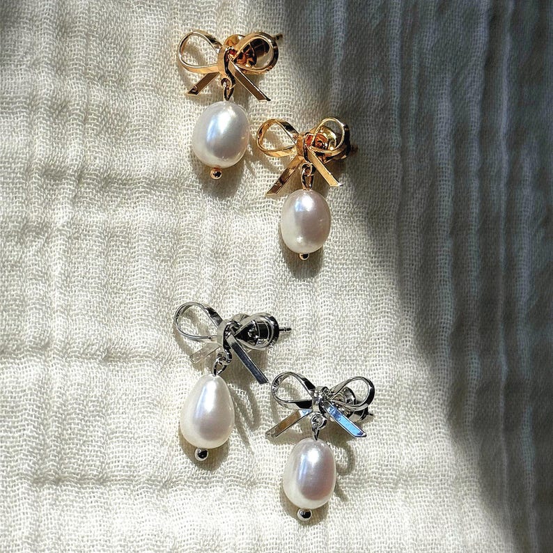 AFlatlay of gold and silver versions of the earrings on striped cloth. A versatile pair for bridal earrings or bridesmaid jewelry styling.