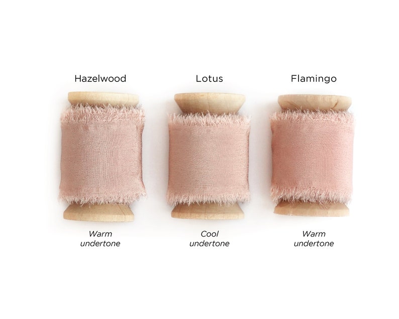 May include: Three spools of pink ribbon, labeled "Hazelwood", "Lotus", and "Flamingo". Each spool has a wooden base and a warm or cool undertone.